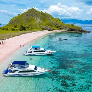 Aerial view of boats by the turquoise waters and pink sand beach at Komodo Island, Indonesia.